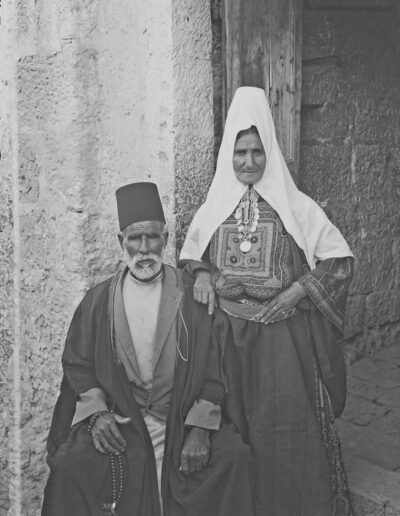 Älteres bethlehemitisches Ehepaar in ihrer traditionellen Kleidung vor ihrem Haus [1918-35, 122]