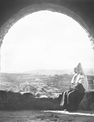 Eine Frau, die die traditionelle Kleidung von Bethlehem trägt, genießt den Blick auf die Hügel von Bethlehem. [1918-35, 115]